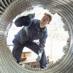 Mann prüft großes elektrisches Bauteil von Innen